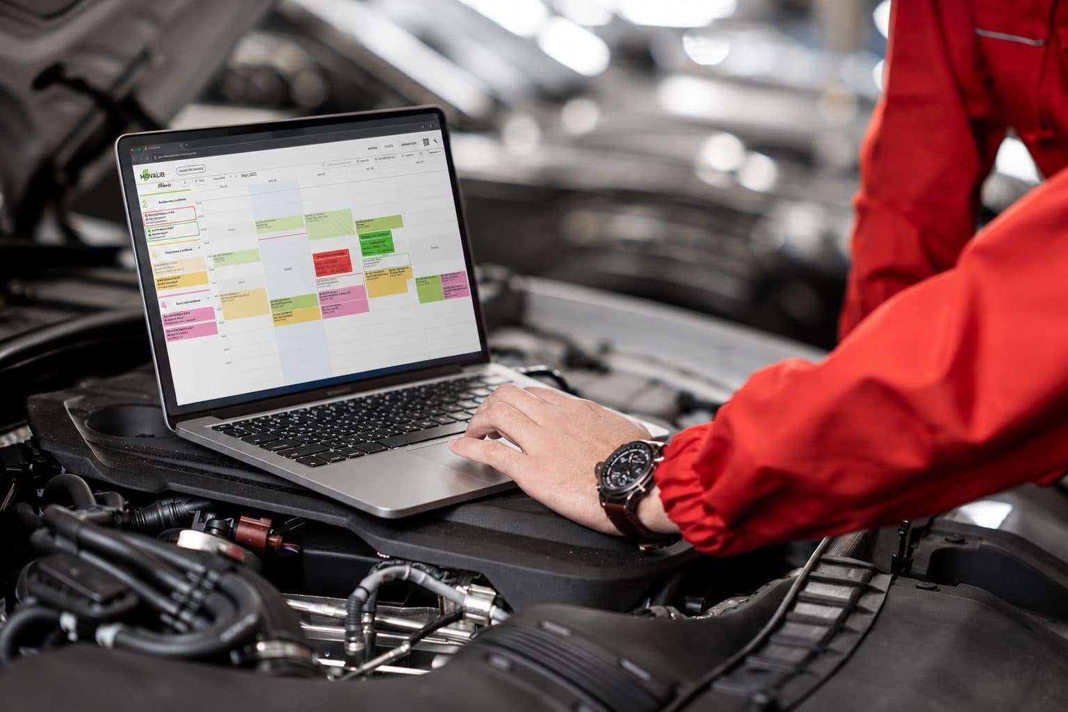 Mécanicien consultant le planning d'atelier d'un logiciel de gestion de garage sur ordinateur portable